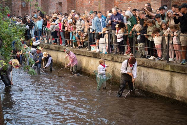 Ein Blick auf das traditionelle Bachausfischen während des Fischertags in Memmingen. Zahlreiche Fischer in teils historischer Kleidung waten durch den Stadtbach, um Fische zu fangen. Dicht gedrängt stehen Zuschauer am Ufer und verfolgen das Spektakel, das jährlich tausende Besucher anzieht. Im Hintergrund sind die historischen Mauern der Stadt zu sehen. Der Memminger Fischertag ist eines der ältesten und bekanntesten Volksfeste in Bayern. Memmingen Bayern Deutschland *** A look at the traditional stream fishing during Fishermen’s Day in Memmingen. Numerous fishermen, some in historical attire, wade through the town stream to catch fish. Spectators stand crowded together on the bank, watching the spectacle, which attracts thousands of