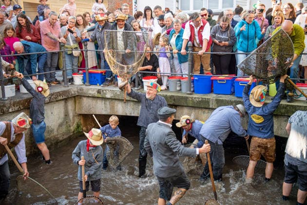 Ein Blick auf das traditionelle Bachausfischen während des Fischertags in Memmingen. Zahlreiche Fischer in teils historischer Kleidung waten durch den Stadtbach, um Fische zu fangen. Dicht gedrängt stehen Zuschauer am Ufer und verfolgen das Spektakel, das jährlich tausende Besucher anzieht. Im Hintergrund sind die historischen Mauern der Stadt zu sehen. Der Memminger Fischertag ist eines der ältesten und bekanntesten Volksfeste in Bayern. Memmingen Bayern Deutschland *** A look at the traditional stream fishing during Fishermen’s Day in Memmingen. Numerous fishermen, some in historical attire, wade through the town stream to catch fish. Spectators stand crowded together on the bank, watching the spectacle, which attracts thousands of