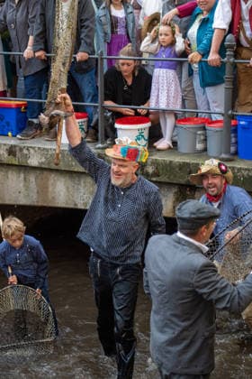 Ein Blick auf das traditionelle Bachausfischen während des Fischertags in Memmingen. Zahlreiche Fischer in teils historischer Kleidung waten durch den Stadtbach, um Fische zu fangen. Dicht gedrängt stehen Zuschauer am Ufer und verfolgen das Spektakel, das jährlich tausende Besucher anzieht. Im Hintergrund sind die historischen Mauern der Stadt zu sehen. Der Memminger Fischertag ist eines der ältesten und bekanntesten Volksfeste in Bayern. Memmingen Bayern Deutschland *** A look at the traditional stream fishing during Fishermen’s Day in Memmingen. Numerous fishermen, some in historical attire, wade through the town stream to catch fish. Spectators stand crowded together on the bank, watching the spectacle, which attracts thousands of