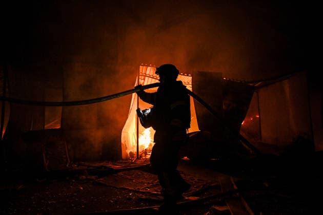 A rescuer extinguishes a fire at a shopping complex caused by a Russian attack in Zaporizhzhia, Ukraine, July 25, 2026. In the early hours of Saturday, July 25, Russian troops struck the southeastern Ukrainian city with drones, igniting a fire that spread through shops and trading pavilions over an area of about 900 square metres. A 63-year-old man was injured in the drone strike. (Photo by Dmytro Smolienko Ukrinform) Russian army attacks Zaporizhzhia with drones  Copyright: xDmytroxSmolienkox