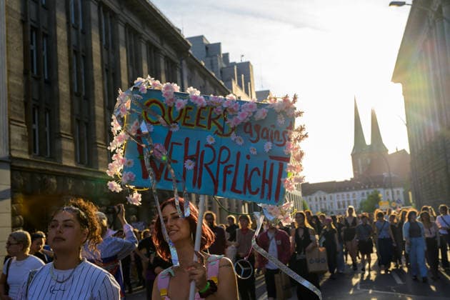 July 24, 2026, Berlin, Berlin, Germany: A person holds a placcard against the mandatory military conscription (Wehrpflicht) decorated with flowers at Dyke* March 2026, on July 24 2026, in Berlin, Germany. Thousands of demonstrators marched in the streets of Berlin s City Center and Kreuzberg districts for the annual Dyke* March just a day before the annual CSD parade and Internationalist Queer Pride Berlin Germany  - ZUMAk201 20260724_zip_k201_007 Copyright: xNikosxKanistrasx
