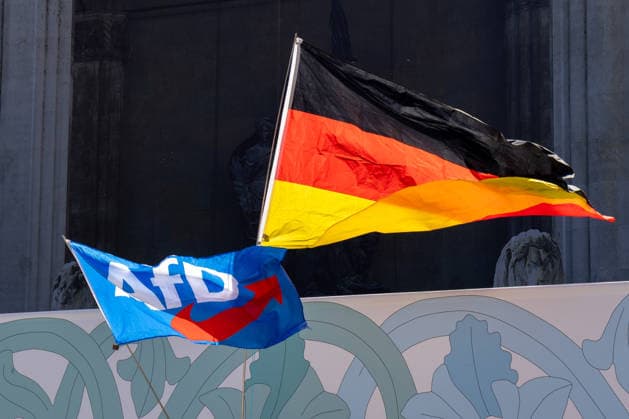 Munich, Bavaria, Germany July 25, 2026: Protesters demonstrate in downtown Munich against Chancellor Friedrich Merz (CDU) and the federal government™s policies. The rally is directed, among other things, against the government™s economic and social policies. A German flag alongside a flag bearing the AfD (Alternative for Germany) logo *** Teilnehmer demonstrieren in der Münchner Innenstadt gegen Bundeskanzler Friedrich Merz (CDU) und die Politik der Bundesregierung. Die Kundgebung richtet sich unter anderem gegen die Regierungs- und Sozialpolitik. Deutschlandfahne zusammen mit einer AfD (Alternative für Deutschland) Logo Flagge