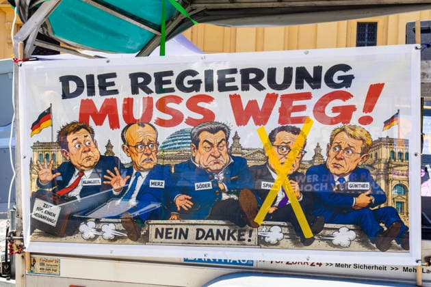 News Bilder des Tages Munich, Bavaria, Germany - July 25, 2026: Protesters demonstrate in downtown Munich against Chancellor Friedrich Merz (CDU) and the federal government s policies. The rally is directed, among other things, against the government™s policies and social policies. A banner reads: THE GOVERNMENT MUST GO!? with illustrations of Lars Klingbeil (SPD), Friedrich Merz (CDU), Markus Söder (CSU), and Jens Spahn (CDU) crossed out, and Daniel Günther (CDU) *** Teilnehmer demonstrieren in der Münchner Innenstadt gegen Bundeskanzler Friedrich Merz (CDU) und die Politik der Bundesregierung. Die Kundgebung richtet sich unter anderem gegen die Regierungs- und Sozialpolitik. Banner mit Aufschrift: DIE REGIERUNG MUSS WEG! mit Illustrationen von Lars K