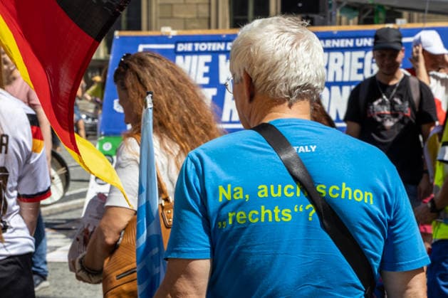 Munich, Bavaria, Germany July 25, 2026: Protesters demonstrate in downtown Munich against Chancellor Friedrich Merz (CDU) and the federal government™s policies. The rally is directed, among other things, against the government™s economic and social policies. A man is wearing a T-shirt with the slogan: Well, are you on the right already? *** Teilnehmer demonstrieren in der Münchner Innenstadt gegen Bundeskanzler Friedrich Merz (CDU) und die Politik der Bundesregierung. Die Kundgebung richtet sich unter anderem gegen die Regierungs- und Sozialpolitik. Ein Mann trägt ein T-Shirt mit Aufschrift: Na, auch schon rechts?