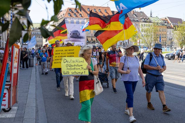 Munich, Bavaria, Germany - July 25, 2026: Protesters demonstrate in downtown Munich against Chancellor Friedrich Merz (CDU) and the federal government s policies. The rally is directed, among other things, against the government s economic and social policies. Protesters carrying German flags and flags of the AfD (Alternative for Germany) party *** Teilnehmer demonstrieren in der Münchner Innenstadt gegen Bundeskanzler Friedrich Merz (CDU) und die Politik der Bundesregierung. Die Kundgebung richtet sich unter anderem gegen die Regierungs- und Sozialpolitik. Demoteilnehmer mit Deutschland Flaggen bzw. Fahnen und Fahnen der Partei AfD (Alternative für Deutschland)