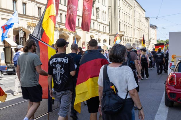Munich, Bavaria, Germany - July 25, 2026: Protesters demonstrate in downtown Munich against Chancellor Friedrich Merz (CDU) and the federal government s policies. The rally is directed, among other things, against the government s economic and social policies. Protesters carrying German flags and flags of the AfD (Alternative for Germany) party *** Teilnehmer demonstrieren in der Münchner Innenstadt gegen Bundeskanzler Friedrich Merz (CDU) und die Politik der Bundesregierung. Die Kundgebung richtet sich unter anderem gegen die Regierungs- und Sozialpolitik. Demoteilnehmer mit Deutschland Flaggen bzw. Fahnen und Fahnen der Partei AfD (Alternative für Deutschland)