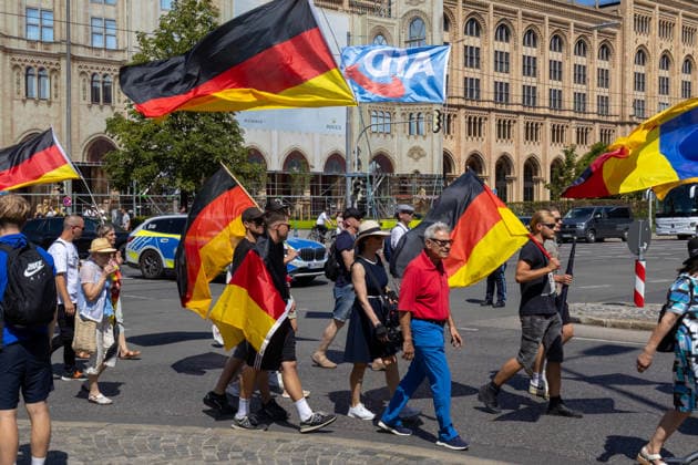 Munich, Bavaria, Germany - July 25, 2026: Protesters demonstrate in downtown Munich against Chancellor Friedrich Merz (CDU) and the federal government s policies. The rally is directed, among other things, against the government s economic and social policies. Protesters carrying German flags and flags of the AfD (Alternative for Germany) party *** Teilnehmer demonstrieren in der Münchner Innenstadt gegen Bundeskanzler Friedrich Merz (CDU) und die Politik der Bundesregierung. Die Kundgebung richtet sich unter anderem gegen die Regierungs- und Sozialpolitik. Demoteilnehmer mit Deutschland Flaggen bzw. Fahnen und Fahnen der Partei AfD (Alternative für Deutschland)