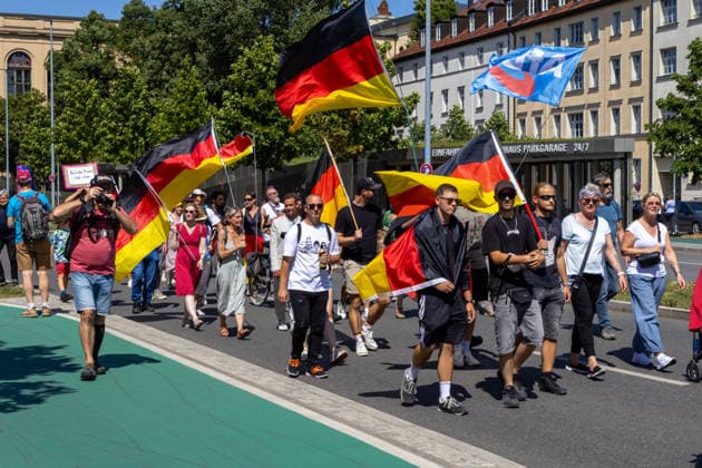 Munich, Bavaria, Germany - July 25, 2026: Protesters demonstrate in downtown Munich against Chancellor Friedrich Merz (CDU) and the federal government s policies. The rally is directed, among other things, against the government s economic and social policies. Protesters carrying German flags and flags of the AfD (Alternative for Germany) party *** Teilnehmer demonstrieren in der Münchner Innenstadt gegen Bundeskanzler Friedrich Merz (CDU) und die Politik der Bundesregierung. Die Kundgebung richtet sich unter anderem gegen die Regierungs- und Sozialpolitik. Demoteilnehmer mit Deutschland Flaggen bzw. Fahnen und Fahnen der Partei AfD (Alternative für Deutschland)