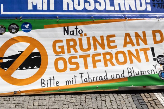 News Bilder des Tages Munich, Bavaria, Germany July 25, 2026: Protesters demonstrate in downtown Munich against Chancellor Friedrich Merz (CDU) and the federal government™s policies. The rally is directed, among other things, against the government™s policies and social policies. Banners and signs read: The dead of the world wars warn us: Never again war with Russia; NATO and the Greens to the Eastern Front! Please bring bicycles and flowers ***? Teilnehmer demonstrieren in der Münchner Innenstadt gegen Bundeskanzler Friedrich Merz (CDU) und die Politik der Bundesregierung. Die Kundgebung richtet sich unter anderem gegen die Regierungs- und Sozialpolitik. Banner bzw. Aufsteller mit Aufchrift: Die Toten der Weltkriege warnen uns: Nie wieder Krieg mi
