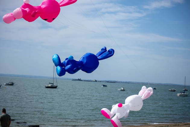 July 25, 2026, Essex, United Kingdom: Giant inflatable rabbit kites in pink, blue and white fly above the sea and moored sailing boats during the Kite Festival at Southend-On-Sea, with a spectator watching from the beach below. The Kite Festival Southend s Alternative Airshow, organised by Project Southchurch, was held on the Eastern Esplanade at Thorpe Bay seafront, Southend-On-Sea, Essex. Essex United Kingdom - ZUMAs197 20260725_aaa_s197_418 Copyright: xIanxDavidsonx