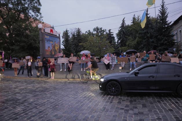 Protest Against Ukrainian President Zelenskiy s Decision To Replace Fedorov As Defence Minister, In Kharkiv Protesters holding signs and umbrellas gather in central Kharkiv, Ukraine, on July 25, 2026, to demonstrate against Ukrainian President Volodymyr Zelenskiy s decision to replace Defence Minister Fedorov with a cyclist passing through the crowd as the blue-and-yellow flag flies above the metro station. The demonstration reflects public concern over military leadership changes amid ongoing conflict with Russian forces. Demonstrators carried cardboard signs expressing their views on the ministerial appointment. Kharkiv Kharkiv Oblast Ukraine  Copyright: xYevhenxTitovx originalFilename: titov-ukrainia260725_npMmZ.jpg
