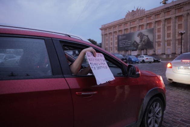 Ukrainians Protest - Kharkiv A protester holds a sign reading text in Ukrainian from the window of a red car during a demonstration against Ukrainian President Volodymyr Zelenskiy s decision to replace Defence Minister Fedorov, in Kharkiv, Ukraine, on July 25, 2026. The demonstration took place in a central square lined with parked vehicles and a distinctive red-brick administrative building, as the protest reflected public concern over the military leadership transition amid ongoing regional tensions. Photo by Yevhen Titov ABACAPRESS.COM Kharkiv Kharkiv Oblast Ukraine  Copyright: xTitovxYevhen ABACAx