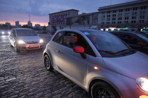 Ukrainians Protest - Kharkiv Drivers display signs and paint their car windows red in protest against Ukrainian President Zelenskiy s decision to replace Fedorov as Defence Minister, in Kharkiv, Ukraine, on July 25, 2026. The evening demonstration saw multiple vehicles parked in the city s central square with red-painted mirrors and protest messages visible through windows, as Soviet-era buildings and the city skyline are illuminated at dusk. Photo by Yevhen Titov ABACAPRESS.COM Kharkiv Kharkiv Oblast Ukraine  Copyright: xTitovxYevhen ABACAx