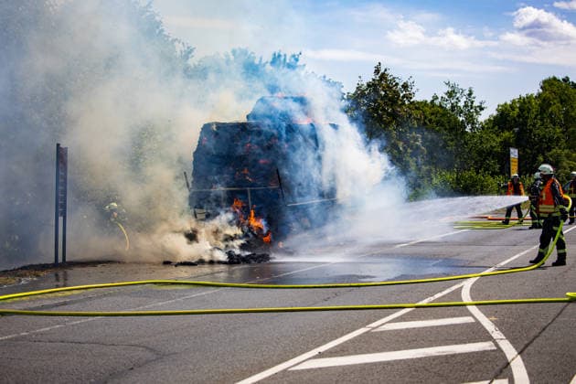 Strohballen fangen auf Anhänger Feuer Landwirt koppelt Traktor ab Flammen greifen auf Vegetation über Am 26.07.2026 geriet auf der L3114 zwischen Groß-Zimmern und Dieburg ein mit Strohquaderballen beladener Anhänger eines Traktors in Brand. Ein Landwirt koppelte nach Hinweisen von Autofahrern den Traktor ab und alarmierte die Feuerwehr, während der Brand auf die gesamte Ladung übergriff. Durch starken Wind breitete sich das Feuer zusätzlich auf einen Grünstreifen und angrenzende Vegetation aus, die Polizei sperrte die Landstraße. Die Feuerwehr Dieburg löschte den Brand mit Unterstützung der Feuerwehr Groß-Zimmern, laut Landwirt liegt eine natürliche Selbstentzündung nahe. Menschen wurden nicht verletzt. Dieburg L3114 H