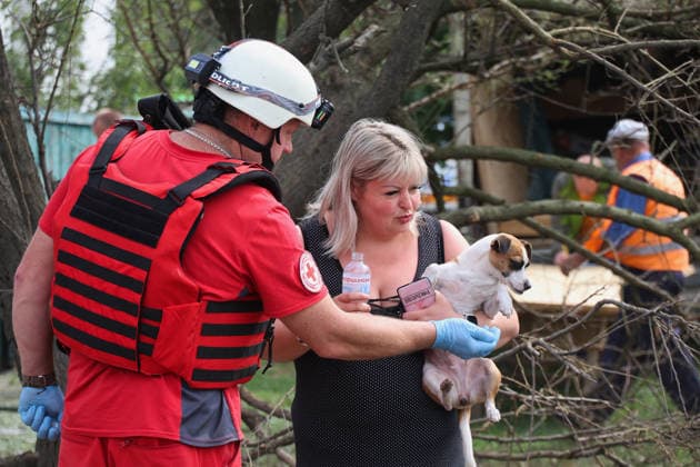 A paramedic helps a woman holding a dog after a direct hit from a Russian S8000 Banderol cruise missile on a residential area in the Slobidskyi district, Kharkiv, Ukraine, July 26, 2026. A 40-year-old woman was killed in the attack, and 12 people were injured. In total, at least 22 private houses and power lines were damaged in the district. (Photo by Viacheslav Madiievskyi Ukrinform) Russians strike residential area in Kharkiv with Banderol missile  Copyright: xViacheslavxMadiievskyix