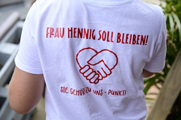 Ein Schüler trägt ein T-Shirt mit der Aufschrift: Frau Hennig soll bleiben. Sie gehört zu uns. Elternprotest - Grundschule Schöpstal droht Lehrerverlust. Große Unruhe zum Ferienbeginn an der Grundschule Schöpstal in Kunnersdorf: Einer langjährigen Klassenlehrerin droht im neuen Schuljahr die vollständige Abordnung an eine andere Schule. Da eine finale Entscheidung des Landesamtes für Schule und Bildung (LaSuB) noch aussteht, blicken viele Familien voller Ungewissheit auf die künftige Unterrichtsversorgung. Die Elternschaft wehrt sich nun massiv gegen den drohenden Unterrichtsausfall, den sie in der Vergangenheit bereits durch private Honorarkräfte im Sportunterricht abfedern musste. Mit einem offenen Brief an Ministerpräsident Copyright: xMatthiasxWehnertx