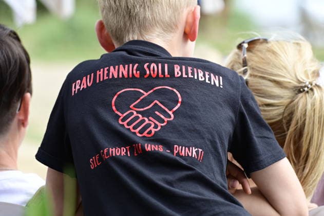 Ein Schüler trägt ein T-Shirt mit der Aufschrift: Frau Hennig soll bleiben. Sie gehört zu uns. Elternprotest - Grundschule Schöpstal droht Lehrerverlust. Große Unruhe zum Ferienbeginn an der Grundschule Schöpstal in Kunnersdorf: Einer langjährigen Klassenlehrerin droht im neuen Schuljahr die vollständige Abordnung an eine andere Schule. Da eine finale Entscheidung des Landesamtes für Schule und Bildung (LaSuB) noch aussteht, blicken viele Familien voller Ungewissheit auf die künftige Unterrichtsversorgung. Die Elternschaft wehrt sich nun massiv gegen den drohenden Unterrichtsausfall, den sie in der Vergangenheit bereits durch private Honorarkräfte im Sportunterricht abfedern musste. Mit einem offenen Brief an Ministerpräsident Copyright: xMatthiasxWehnertx