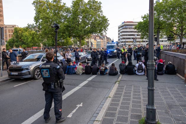 Montagsdemo Team Menschenrechte mit Gegendemonstration und Blockaden, Nürnberg, 27.07.2026 Mehrere Personen sitzen auf der Straße und blockieren eine Kreuzung im Rahmen einer Gegendemonstration. Zahlreiche Polizeikräfte in Uniform sichern die Örtlichkeit und beobachten die Sitzblockade. Einsatzfahrzeuge der Polizei stehen im Hintergrund bereit. Nürnberg Bayern Deutschland *** Monday Demonstration: Human Rights Team Holds a Counter-Demonstration and Sets Up Blockades, Nuremberg, July 27, 2026 Several people are sitting on the street and blocking an intersection as part of a counter-demonstration. Numerous uniformed police officers are securing the area and monitoring the sit-in. Police emergency vehicles are standing by in the backgr 20260727-286A3087-M4000