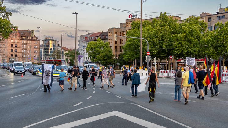 Montagsdemo Team Menschenrechte mit Gegendemonstration und Blockaden, Nürnberg, 27.07.2026 Demonstranten mit Fahnen und Transparenten überqueren eine mehrspurige Kreuzung am Plärrer und blockieren dabei den Straßenverkehr. Polizeikräfte begleiten den Aufzug, während wartende Fahrzeuge die Sperrung der Kreuzung verdeutlichen. Die Straßensperrung betrifft den gesamten Innenstadtbereich und führt zu Verärgerung bei Autofahrern. Nürnberg Bayern Deutschland *** Monday Demonstration Human Rights Team with a counter-demonstration and roadblocks, Nuremberg, July 27, 2026. Demonstrators carrying flags and banners cross a multi-lane intersection at Plärrer, blocking traffic in the process. Police officers escort the march, while waitin 20260727-286A3159-M4000