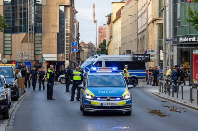 Montagsdemo Team Menschenrechte mit Gegendemonstration und Blockaden, Nürnberg, 27.07.2026 Mehrere Polizeifahrzeuge mit Blaulicht sichern eine Innenstadtstraße im Rahmen einer angemeldeten Versammlung. Zahlreiche Polizeikräfte in Uniform und Warnwesten stehen bereit, im Hintergrund ein Hinweisschild mit der Aufschrift Versammlung folgt. Passanten und Schaulustige beobachten das Geschehen am Straßenrand. Nürnberg Bayern Deutschland *** Monday Demonstration Human Rights Team Holds Counter-Demonstration and Blockades, Nuremberg, July 27, 2026. Several police vehicles with flashing lights are securing a downtown street as part of a registered assembly. Numerous police officers in uniform and high-visibility vests stand by, with a sign 20260727-6V2A0092-M4000