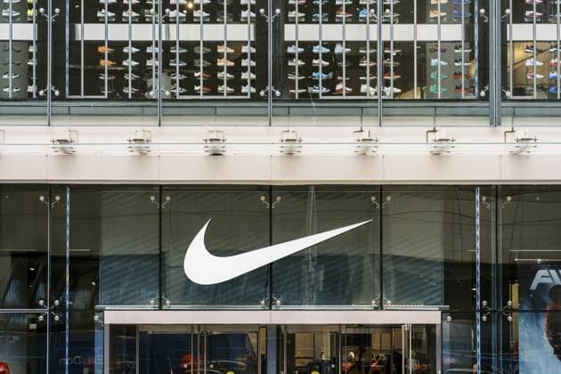 Das Äußere eines Nike Einzelhandelsgeschäfts mit einem großen weißen Nike Swoosh Logo auf Glasscheiben. In den Regalen im Geschäft sind auffällige farbenfrohe Sneaker angeordnet The exterior of a Nike retail store featuring a large white Nike Swoosh logo on glass panels, with a prominent display of colorful sneakers arranged on shelves inside the store Copyright: imageBROKER NadtochiyxPhotograph ibliqx18496506.jpg