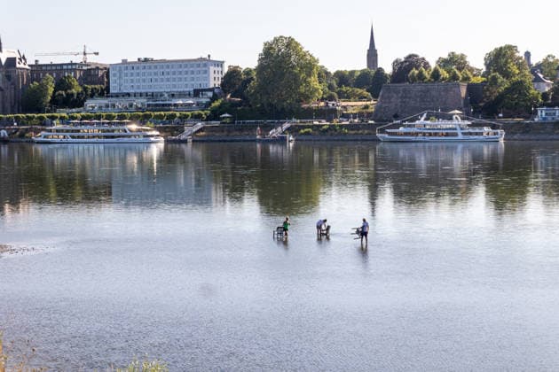 Niedrigwasser am Rhein: Menschen genießen den Sommer im flachen Wasser bei Bonn-Beuel Bonn-Beuel, 28.07.2026: Menschen sitzen auf Campingstühlen im nur wenige Zentimeter tiefen Wasser am Rheinufer in Bonn-Beuel und genießen bei sommerlichen Temperaturen die Sonne. Der außergewöhnlich niedrige Wasserstand hat weite Bereiche des Ufers und Sandbänke freigelegt. Am Pegel Bonn wurde am Morgen des 28. Juli ein Wasserstand von nur 89 Zentimetern gemessen. Das anhaltende Niedrigwasser beeinträchtigt die Schifffahrt und ist Ausdruck der trockenen Witterung. Bonn Beuel Nordrhein-Westfalen Deutschland *** Low Water Levels on the Rhine: People Enjoy the Summer in Shallow Water Near Bonn Beuel Bonn Beuel, July 28, 2026 People are sitting on campi