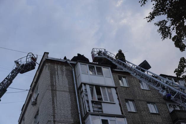 Shahed Drone Strike - Kharkiv A firefighter in a white helmet stands in an aerial ladder platform bucket at rooftop level as two fire truck ladders are deployed to extinguish a blaze on the burned-out roof of a five-story residential brick apartment building struck by a russian Shahed-type reactive drone in the Novobavarski district of Kharkiv, Ukraine, on July 28, 2026, after the roof structure sustained significant fire damage, with charred debris visible along the roofline, while the building s facade and balconies show signs of blast impact; all residents were evacuated, and two people were reported injured as emergency crews continued to eliminate the consequences of the russian drone attack. Photo by Titov Yevhen ABACAPRESS.COM Kharki  Copyright: xTitovxYevhen ABACAx
