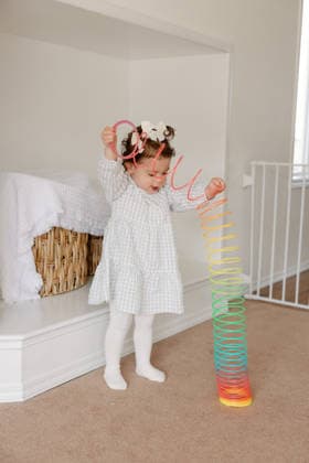 Curious toddler stretches a colourful spring toy at home Calgary, Alberta, Canada CR_CUYS260722-2086751-01 ,model released, Symbolfoto ,property released