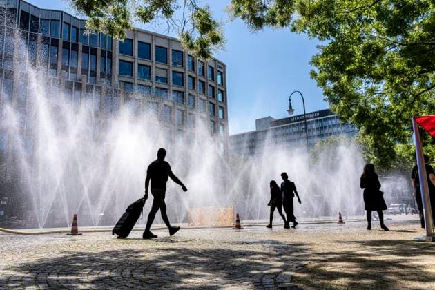 Cooling Cologne, Aktion der Stadt Köln zur Abkühlung von Hitzebelasteten Plätzen, hier der Rudolfplatz in der Innenstadt, bei knapp 37Â°C an dem Tag, ein Sprühschlauch verspritzt feine Wassertröpfen, die die unmittelbare Umgebung einige Grade abkühlt, eine Aktion die bei extremer Hitzebelastung vorgenommen wird, zur Anpassung des Stadtklimas an den Klimawandel, Passanten genießen den kühlenden Moment, dazu gibts Tipps zum Umgang mit Extremhitze, NRW, Deutschland, Extremhitze *** Cooling Cologne, a City of Cologne initiative to cool down areas affected by heat, here at Rudolfplatz in the city center, with temperatures nearing 37°C that day, a spray hose disperses fine droplets of water that cool the immediate surroundings by a few de