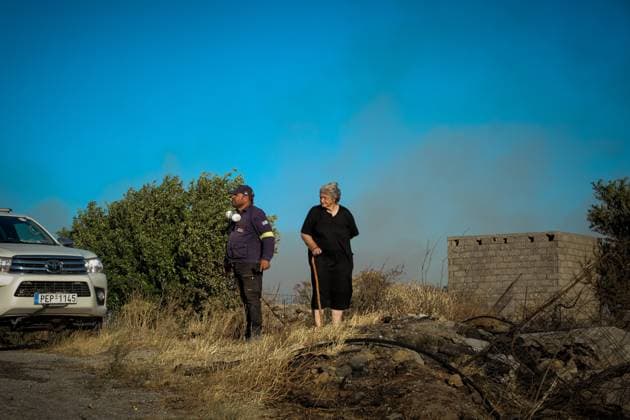 (260730) -- CRETE, July 30, 2026 -- A firefighter and a resident check an area affected by a wildfire in Rethymno on the island of Crete, Greece, July 29, 2026. Two firefighters lost their lives while battling a fast-moving wildfire in Rethymno on the Greek island of Crete on Wednesday, as gale-force winds fueled the blaze across a front stretching more than 15 kilometers. (Photo by Xinhua) GREECE-CRETE-WILDFIRE-FIREFIGHTERS RapanisxSpiros 