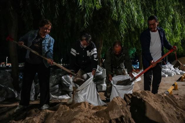 (260730) -- DUNHUANG, July 30, 2026 -- Local officials and residents stack sandbags to fortify the embankment along the Danghe River in Dunhuang, northwest China s Gansu Province, July 29, 2026. The water level of the Danghe River, which runs through Dunhuang City in northwest China s Gansu Province, rose rapidly following days of heavy rainfall and increased inflows from upstream. Local personnel in Dunhuang quickly mobilized for flood control and relief operations. ) CHINA-GANSU-DUNHUANG-FLOOD CONTROL (CN) LangxBingbing 