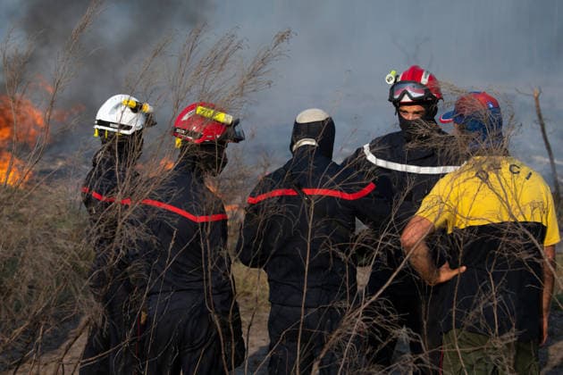 Wildfire Near Le Temple - Gironde Firefighters and a forestry officer coordinate strategy on the fire line during wildfire suppression operations near Le Temple, Gironde, southwestern France, on July 29, 2026. Flames burn through dry vegetation as crews assess fire behavior and organize the next stage of the firefighting operation.  Copyright: xSaptexFabrice ABACAx