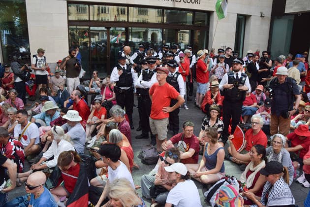 July 30, 2026, London, England, United Kingdom: Pro-Palestine protesters sit outside Westminster Magistrates Court during the so-called Graduation Day protest organised by Defend Our Juries. Police reportedly made arrests on unspecified charges as well as alleged support for the activist group Palestine Action, which is proscribed in the UK. London United Kingdom - ZUMAv130 20260730_zip_v130_024 Copyright: xVukxValcicx