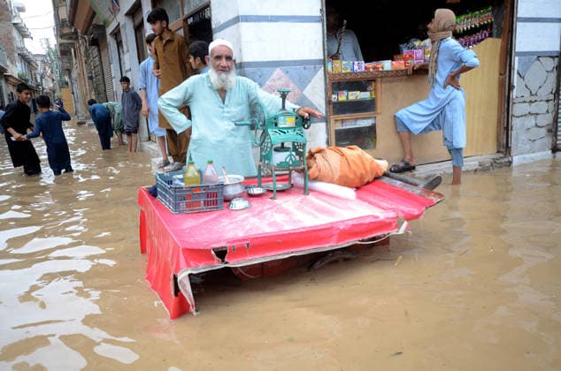 July 31, 2026, Peshawar, Peshawar, Pakistan: A merchant works as people wade through a flooded street during heavy monsoon rain in Peshawar, Khyber Pakhtunkhwa province, Pakistan. Pakistan s Meteorological Department (PMD) forecast the current monsoon spell to continue until August 5, warning of widespread rain, thunderstorms, heavy to very heavy downpours, and the risk of urban flooding, flash floods, landslides and river flooding across parts of the country. Peshawar Pakistan  - ZUMAa217 20260731_znp_a217_029 Copyright: xHussainxAlix