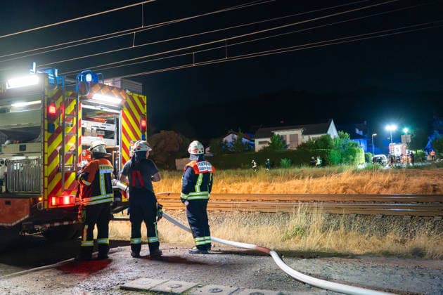 Großer Flächenbrand bedroht Wohngebiet Am 03.08.2026 gegen 02:00 Uhr brannten zwischen Seeheim-Jugenheim und Alsbach im Landkreis Darmstadt-Dieburg rund 28.000 Quadratmeter Feld und Gestrüpp entlang der L3100. Die Feuerwehr stoppte die Flammen etwa fünf Meter vor angrenzenden Wohnhäusern. Ein Anwohner erlitt beim eigenständigen Löschversuch eine Rauchgasvergiftung und wurde vom Rettungsdienst in ein Krankenhaus gebracht. Die Straßenbahnstrecke zwischen Alsbach und Seeheim-Jugenheim wurde gesperrt, ein Schienenersatzverkehr eingerichtet. Zur Brandbekämpfung kam eine Drohne mit Wärmebildkamera zum Aufspüren von Glutnestern zum Einsatz. Seeheim-Jugenheim Hessen Deutschland *** Large Wildfire Threatens Residential Area On August 3,