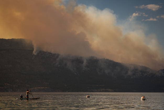 August 3, 2026, Lake Country, Bc, CANADA: A man paddles a paddleboard on Okanagan Lake, in Lake Country, B.C., as the Quilpituk Creek wildfire burns on the mountainside across the lake, near Fintry, on Monday, Aug. 3, 2026. Lake Country CANADA  - ZUMAc35_ 20260803_zaf_c35_122 Copyright: xDarrylxDyckx