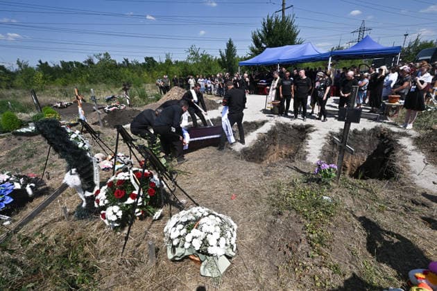 Men lower a coffin into a grave during the funeral of members of the Voronov family, killed when a Russian Iskander-M ballistic missile directly struck their home on the night of Thursday, July 30, Radushne settlement, Kryvyi Rih district, Dnipropetrovsk region, Ukraine, August 3, 2026. Five family members whose identities have been officially confirmed were laid to rest: parents Artem, 47, and Olena, 41, together with their children Mark, 17, Azarii Ilai, 11, and Emiliia, 6. Five other children who were in the house that night - Zakhar, Dominika, Viorika, Federika and one-and-a-half-year-old grandson Artem - are still officially listed as missing. Rescuers recovered 17 body fragments from the rubble, and complex forensic DNA examinations a  Copyright: xDmytroxSmolienkox