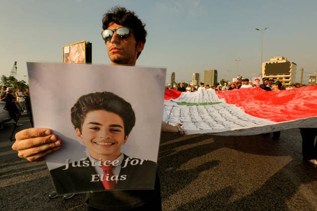 August 4, 2026, Beirut, Beirut, Lebanon: A Lebanese activist holds the picture of Elias Khoury, a 15-year-old victim of Beirut 2020 Beirut port blast as he stands in front of a huge Lebanese flag during a ceremony to mark the six anniversary of the massive explosion that killed more than 200 people and injuring more than 6,500 others. Lebanese authorities have said the explosion was triggered by a fire in a warehouse where tones of ammonium nitrate fertilizer had been stored haphazardly for years, despite repeated warnings to senior officials. Beirut Lebanon - ZUMAn313 20260804_zip_n313_005 Copyright: xMarwanxNaamanix