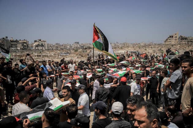 Gaza City Mass Funeral August 3 2026 Mourners carry bodies wrapped in Palestinian flags on stretchers during a mass funeral procession in the Al-Sabra neighborhood of Gaza City, Gaza Strip, on August 4, 2026. The remains of 112 members of the Abu Sharia and Al-Hasayneh families were recovered from the rubble of their home following an Israeli strike. Relatives stated the attack claimed the lives of more than 300 people. The bodies were buried at Al-Maamadani Cemetery as military operations continue across the territory. Gaza Gaza Strip Palestinian Territories Copyright: xMohammedxMxSkaikx