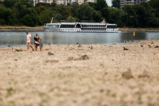 Spaziergänger stehen im ausgetrockneten Teil des Flussbett - im Hintergrund eine Rheinfähre. Der Rheinpegel ist in Köln und Bonn auf einem Rekordtief. Viele Rheinwiesen sind verdorrt und versteppt und der sonst so stolze Fluss hat sich tief in sein Bett zurückgezogen, gibt den Blick auf trockene Ufer frei. Der Pegel lag am Wochenende mit 67 cm so tief wie noch nie seit der Messung. (Themenbild, Symbolbild) Köln, 29.07.2026 NRW Deutschland *** Walkers stand in the dried-up part of the riverbed; a Rhine ferry is visible in the background. The Rhine’s water level in Cologne and Bonn is at a record low. Many Rhine meadows have withered and turned into steppe, and the river—usually so mighty—has receded deep into its bed, revealing dry bank Copyright: xChristophxHardtx