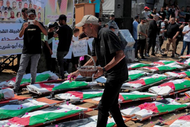 Gaza City Mass Funeral August 3 2026 A man throws flower petals over bodies wrapped in Palestinian flags during a mass funeral procession in the Al-Sabra neighborhood of Gaza City, Gaza Strip, on August 4, 2026. The remains of 112 members of the Abu Sharia and Al-Hasayneh families were recovered from the rubble of their home following an Israeli strike. Relatives stated the attack claimed the lives of more than 300 people. The bodies were buried at Al-Maamadani Cemetery as military operations continue across the territory. Gaza Gaza Strip Palestinian Territories Copyright: xEyadxAzamx