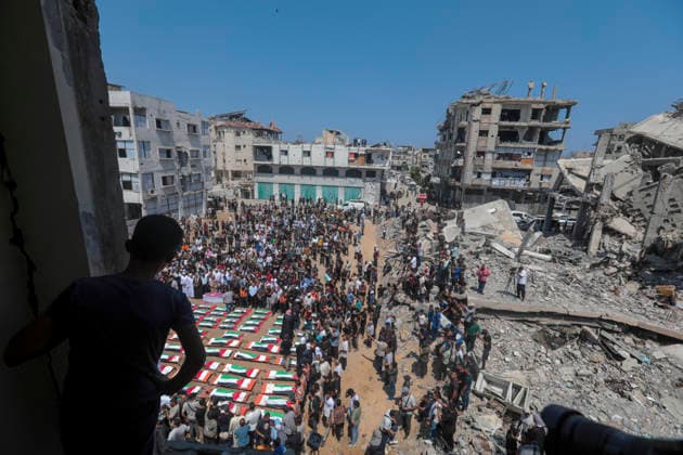 Gaza City Mass Funeral August 3 2026 Mourners gather around rows of bodies wrapped in Palestinian flags during a mass funeral procession in the Al-Sabra neighborhood of Gaza City, Gaza Strip, on August 4, 2026. The remains of 112 members of the Abu Sharia and Al-Hasayneh families were recovered from the rubble of their home following an Israeli strike. Relatives stated the attack claimed the lives of more than 300 people. The bodies were buried at Al-Maamadani Cemetery as military operations continue across the territory. Gaza Gaza Strip Palestinian Territories Copyright: xEyadxAzamx