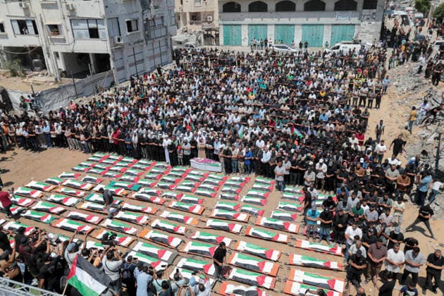Gaza City Mass Funeral August 3 2026 Mourners stand in rows to pray near bodies wrapped in Palestinian flags during a mass funeral procession in the Al-Sabra neighborhood of Gaza City, Gaza Strip, on August 4, 2026. The remains of 112 members of the Abu Sharia and Al-Hasayneh families were recovered from the rubble of their home following an Israeli strike. Relatives stated the attack claimed the lives of more than 300 people. The bodies were buried at Al-Maamadani Cemetery as military operations continue across the territory. Gaza Gaza Strip Palestinian Territories Copyright: xEyadxAzamx