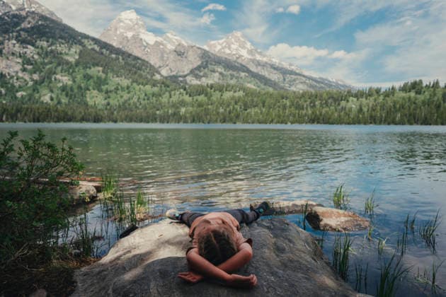 Young child resting on a rock beside a mountain lake. Jackson, Wyoming, United States CR_TYRI26071521-2078193-01 ,model released, Symbolfoto ,property released