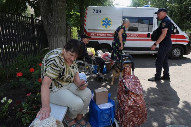 A State Emergency Service worker stands by elderly people sitting on a bench next to an ambulance at an evacuation hub in Kharkiv, Ukraine, August 4, 2026. Evacuation efforts have been intensified in the Kharkiv region, mainly in the Shevchenkove and Staryi Saltiv settlement communities, due to constant Russian bombardment of civilians. (Photo by Viacheslav Madiievskyi Ukrinform) Evacuation hub in Kharkiv  Copyright: xViacheslavxMadiievskyix