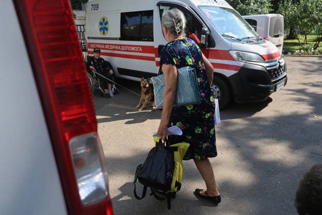 A woman carries a backpack past an ambulance at an evacuation hub in Kharkiv, Ukraine, August 4, 2026. Evacuation efforts have been intensified in the Kharkiv region, mainly in the Shevchenkove and Staryi Saltiv settlement communities, due to constant Russian bombardment of civilians. (Photo by Viacheslav Madiievskyi Ukrinform) Evacuation hub in Kharkiv  Copyright: xViacheslavxMadiievskyix