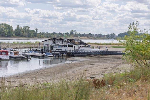 Sürther Bootshaus in Köln einen Tag nach dem Großbrand Ein Tag nach dem Großbrand: Das Sürther Bootshaus in Köln-Sürth, ein beliebtes Ausflugslokal und Restaurant direkt am Rhein, liegt in Trümmern bei dem Feuer am 04.08.2026 brannte vor allem der Dachbereich vollständig aus. Rund 100 Einsatzkräfte der Feuerwehr waren im Großeinsatz, verletzt wurde niemand, die Brandursache ist weiterhin unklar. Köln Sürth Nordrhein-Westfalen Deutschland *** The Sürth Boathouse in Cologne, One Day After the Major Fire One day after the major fire, the Sürth Boathouse in Cologne-Sürth, a popular destination for day trips and a restaurant right on the Rhine, lies in ruins following the fire on August 4, 2026. The roof area, in particular, bur Copyright: xMarcxJohnx