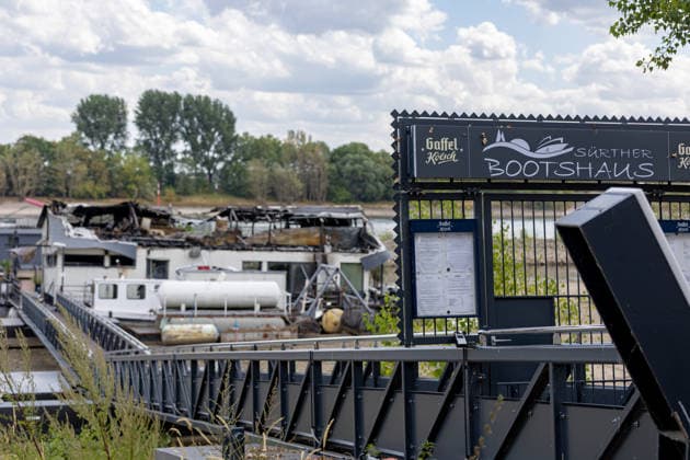 Sürther Bootshaus in Köln einen Tag nach dem Großbrand Ein Tag nach dem Großbrand: Das Sürther Bootshaus in Köln-Sürth, ein beliebtes Ausflugslokal und Restaurant direkt am Rhein, liegt in Trümmern bei dem Feuer am 04.08.2026 brannte vor allem der Dachbereich vollständig aus. Rund 100 Einsatzkräfte der Feuerwehr waren im Großeinsatz, verletzt wurde niemand, die Brandursache ist weiterhin unklar. Köln Sürth Nordrhein-Westfalen Deutschland *** The Sürth Boathouse in Cologne, One Day After the Major Fire One day after the major fire, the Sürth Boathouse in Cologne-Sürth, a popular destination for day trips and a restaurant right on the Rhine, lies in ruins following the fire on August 4, 2026. The roof area, in particular, bur Copyright: xMarcxJohnx