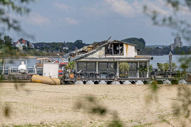 Sürther Bootshaus in Köln einen Tag nach dem Großbrand Ein Tag nach dem Großbrand: Das Sürther Bootshaus in Köln-Sürth, ein beliebtes Ausflugslokal und Restaurant direkt am Rhein, liegt in Trümmern bei dem Feuer am 04.08.2026 brannte vor allem der Dachbereich vollständig aus. Rund 100 Einsatzkräfte der Feuerwehr waren im Großeinsatz, verletzt wurde niemand, die Brandursache ist weiterhin unklar. Köln Sürth Nordrhein-Westfalen Deutschland *** The Sürth Boathouse in Cologne, One Day After the Major Fire One day after the major fire, the Sürth Boathouse in Cologne-Sürth, a popular destination for day trips and a restaurant right on the Rhine, lies in ruins following the fire on August 4, 2026. The roof area, in particular, bur Copyright: xMarcxJohnx
