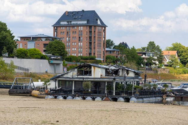 Sürther Bootshaus in Köln einen Tag nach dem Großbrand Ein Tag nach dem Großbrand: Das Sürther Bootshaus in Köln-Sürth, ein beliebtes Ausflugslokal und Restaurant direkt am Rhein, liegt in Trümmern bei dem Feuer am 04.08.2026 brannte vor allem der Dachbereich vollständig aus. Rund 100 Einsatzkräfte der Feuerwehr waren im Großeinsatz, verletzt wurde niemand, die Brandursache ist weiterhin unklar. Köln Sürth Nordrhein-Westfalen Deutschland *** The Sürth Boathouse in Cologne, One Day After the Major Fire One day after the major fire, the Sürth Boathouse in Cologne-Sürth, a popular destination for day trips and a restaurant right on the Rhine, lies in ruins following the fire on August 4, 2026. The roof area, in particular, bur Copyright: xMarcxJohnx